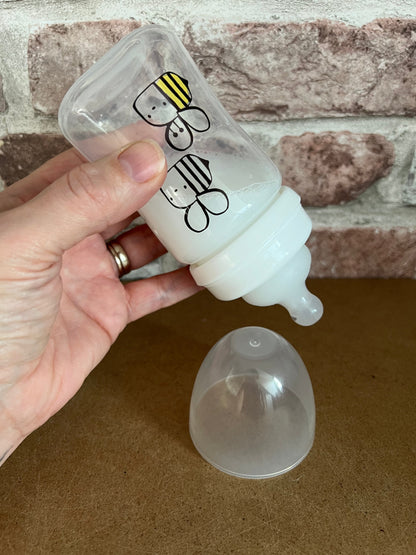 "Bottle with a cartoon character label held by a hand against a stone wall  background willow tree reborns UK"