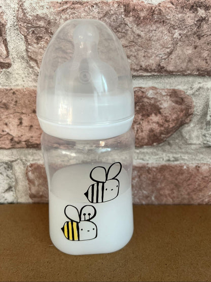 "Clear baby bottle with bee designs on a brick wall background willow tree reborns UK"